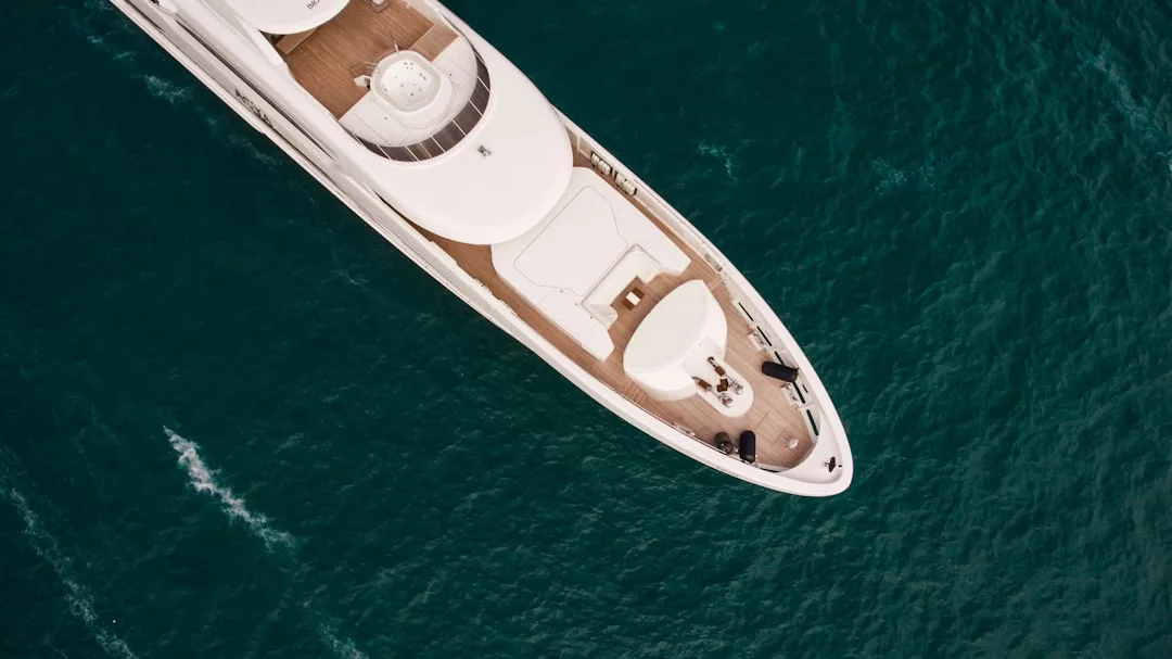 Luftaufnahme einer großen weißen Yacht, die auf dem tiefblauen Wasser in der Nähe von Mallorca segelt, mit Blick auf das Deck und einen Teil der oberen Struktur.