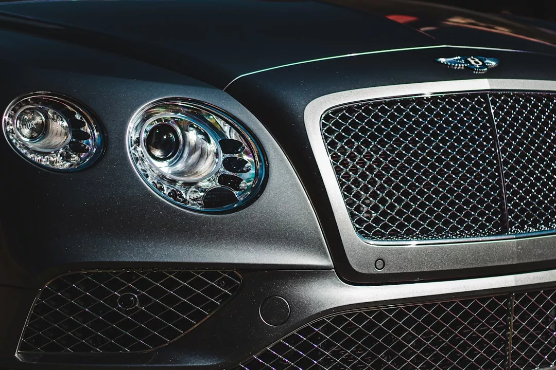 Nahaufnahme des vorderen Kühlergrills und der Scheinwerfer eines schwarzen Bentleys auf Mallorca, mit dem Bentley-Emblem und dem detaillierten Maschenmuster des Kühlergrills.